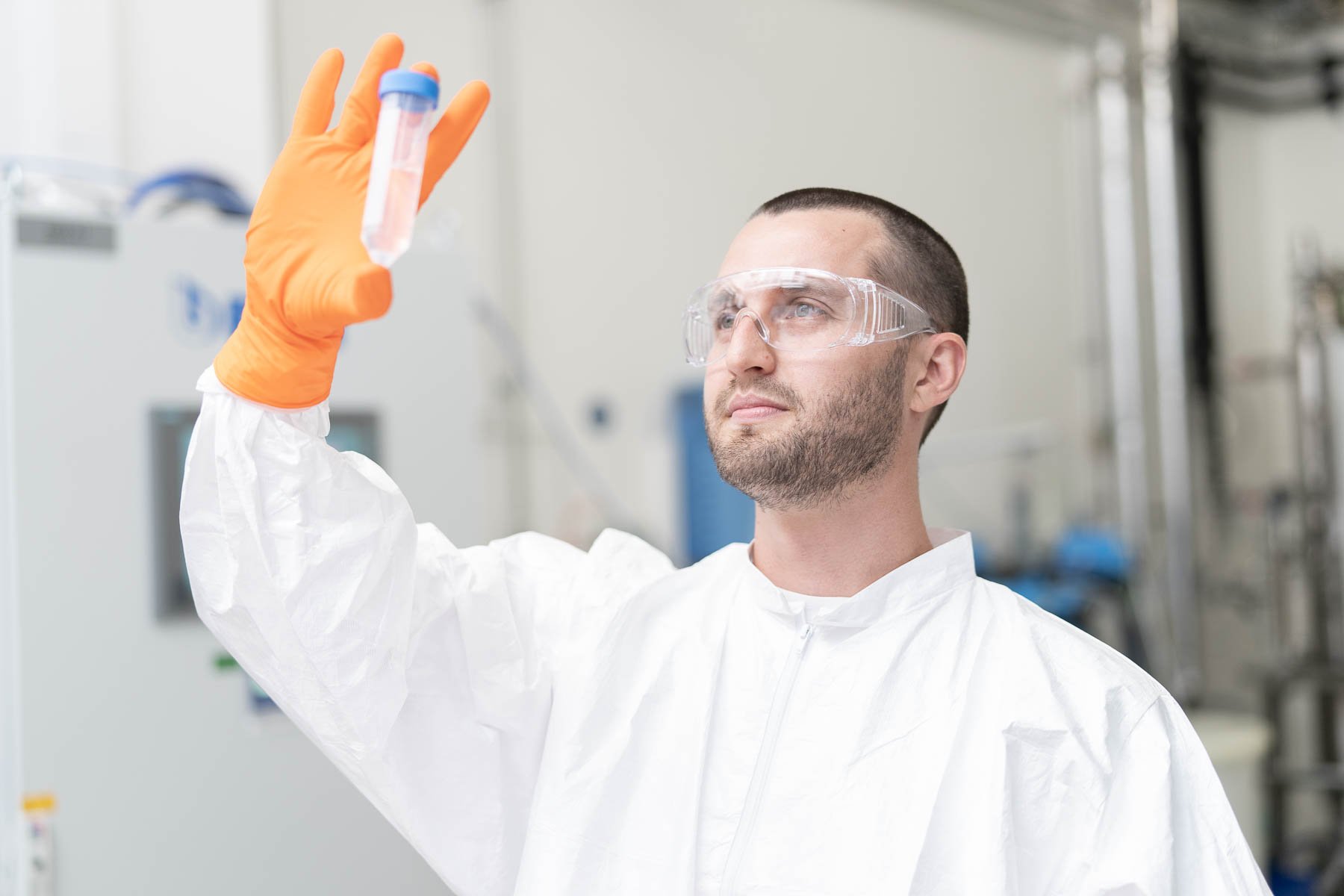 An AGC Biologics employee examines a large vial.
