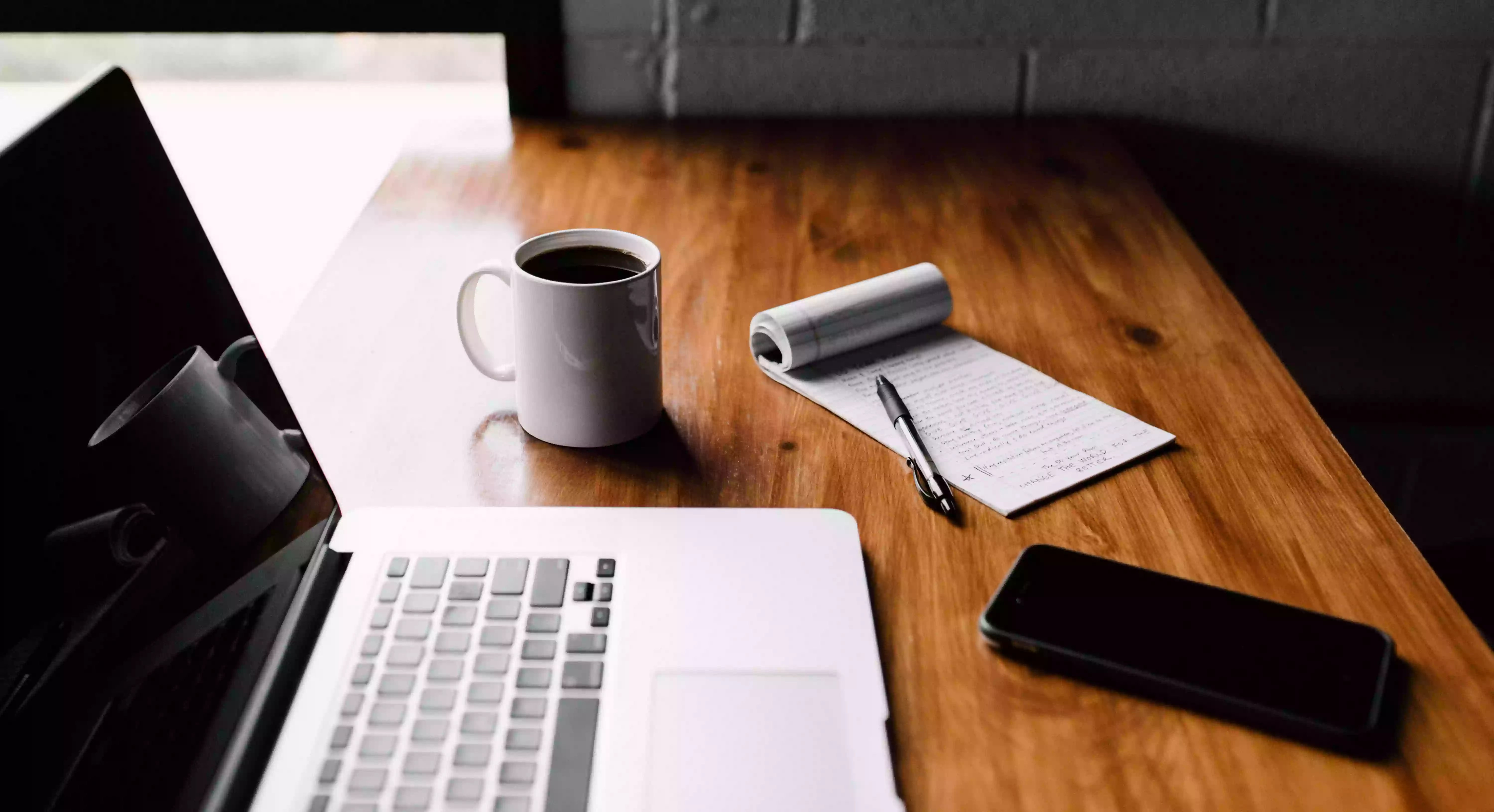 computer and notepad on wooden desk