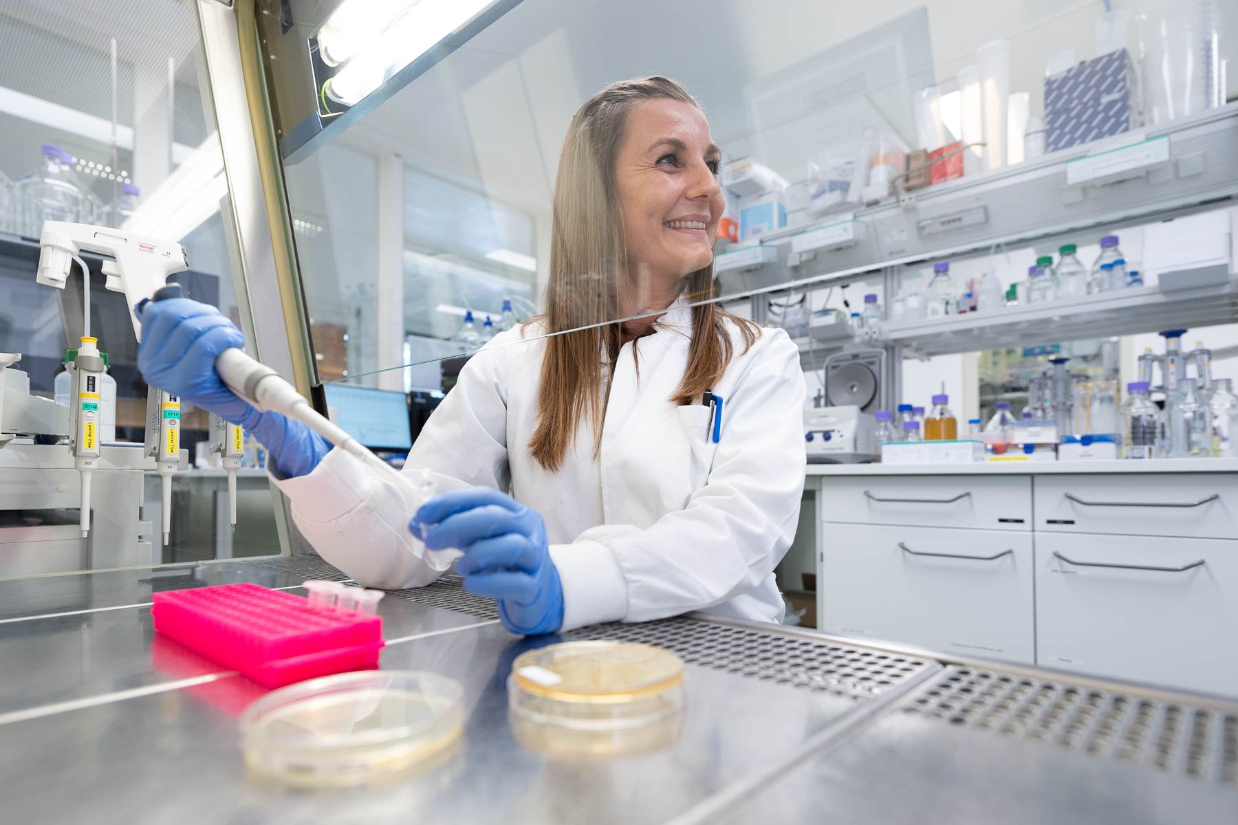 Scientist using a pipette and petri dishes.