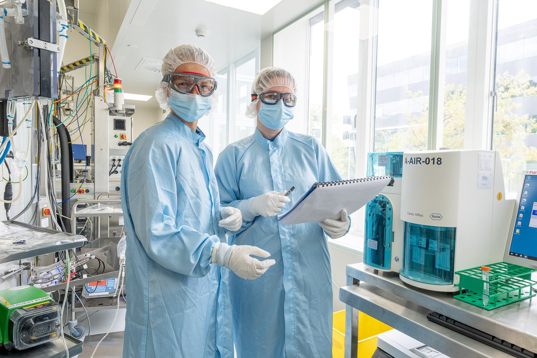 Scientists in PPE looking at documentation in a laboratory.